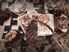 на столе много корзин с едой с клетчатой скатертью