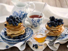 блинчики с черникой и медом на тарелке
