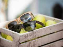 есть два деревянных ящика с солнцезащитными очками и яблоками в них