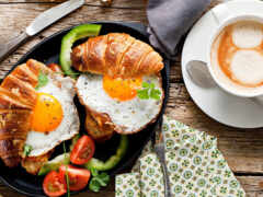 есть тарелка еды с круассаном и чашка кофе