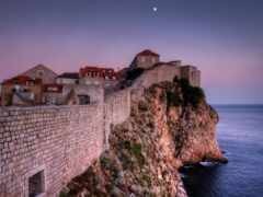 женский вид на каменную стену со зданием на ее вершине