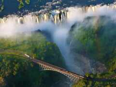 арафы, пересекающие мост через водопад с радугой на заднем плане