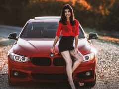 араф позирует рядом с красной машиной на гравийной дороге