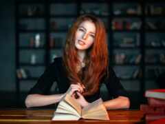 женщина сидит за столом с книгой