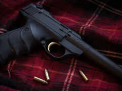 женский пистолет с пулей на клетчатом одеяле с пулей