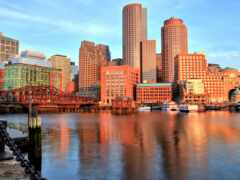 здания отражаются в воде реки в городе