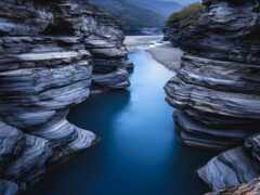 женский каньон с протекающей через него рекой и стоящим на краю человеком