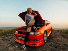 на капоте автомобиля сидит женщина