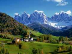 горы со снежными вершинами вдалеке и небольшая деревня на переднем плане