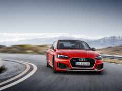 красный автомобиль audi, едущий по извилистой дороге с горами на заднем плане