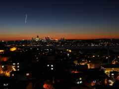 женский вид на город ночью с реактивным самолетом, летящим над городом