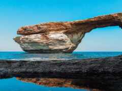 женское скалообразование посреди океана с отражением