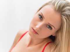 блондинка в красном бюстгальтере смотрит в камеру с серьезным взглядом