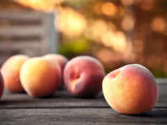 пять персиков сидят на столе с размытым фоном