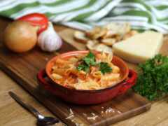 есть чаша макарон и некоторые овощи на разделочной доске