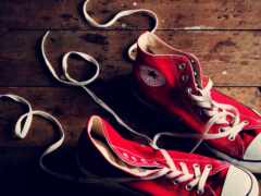 пара красных кроссовок с белыми шнурками на деревянном полу