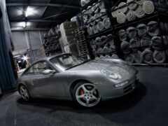 женщина порше припаркована на складе со стопками шин