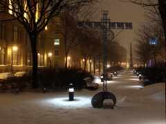 снежный тротуар со скамейками и уличными фонарями в снежную ночь