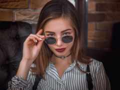 женщина с солнцезащитными очками и ожерелье, держащее пару очков