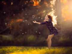 девушка в платье, сдувающая пузыри в поле
