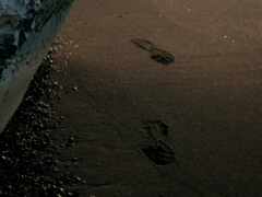 следы на песке пляжа с входящей волной