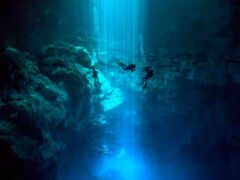 человек ныряет в глубокой голубой пещере