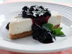 есть кусок чизкейка с черничным соусом на тарелке
