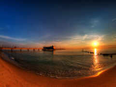 женский вид на пляж с пирсом и закатом