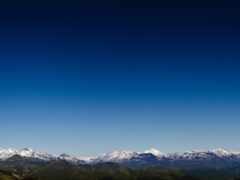 горы со снежными вершинами вдалеке и голубым небом