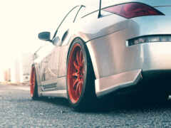 серебряный автомобиль с красными ободками припаркован на улице