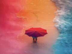 на пляже стоит человек с зонтиком