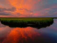 женское небо с розовым и оранжевым закатом, отражающимся в реке