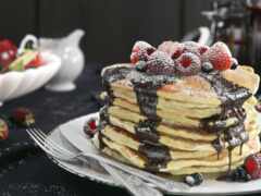 блинчики с шоколадным соусом и ягодами на тарелке