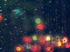 женский вид на окно с каплями дождя и красочными огнями