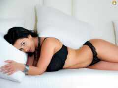 женщина в черном белье, лежащая на белом диване