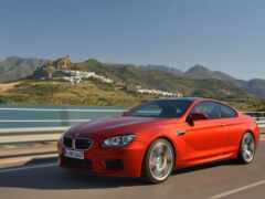 арафированный красный автомобиль bmw, едущий по шоссе рядом с водоемом