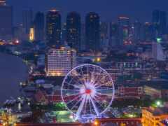 необычный вид на город ночью с колесом обозрения на переднем плане