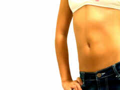 есть женщина в белом топе и джинсах, держащая руки в карманах