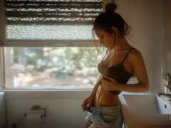 есть женщина, стоящая в ванной комнате с открытым желудком