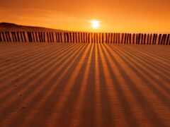 женский вид на забор на пляже с заходом солнца