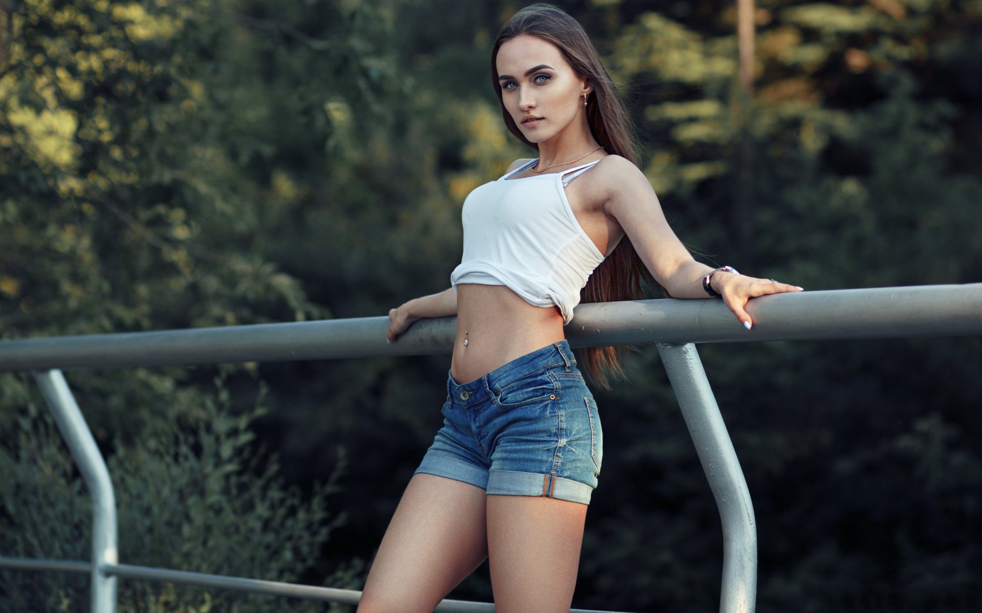 женщина в белой футболке и синих шортах, опирающаяся на перила