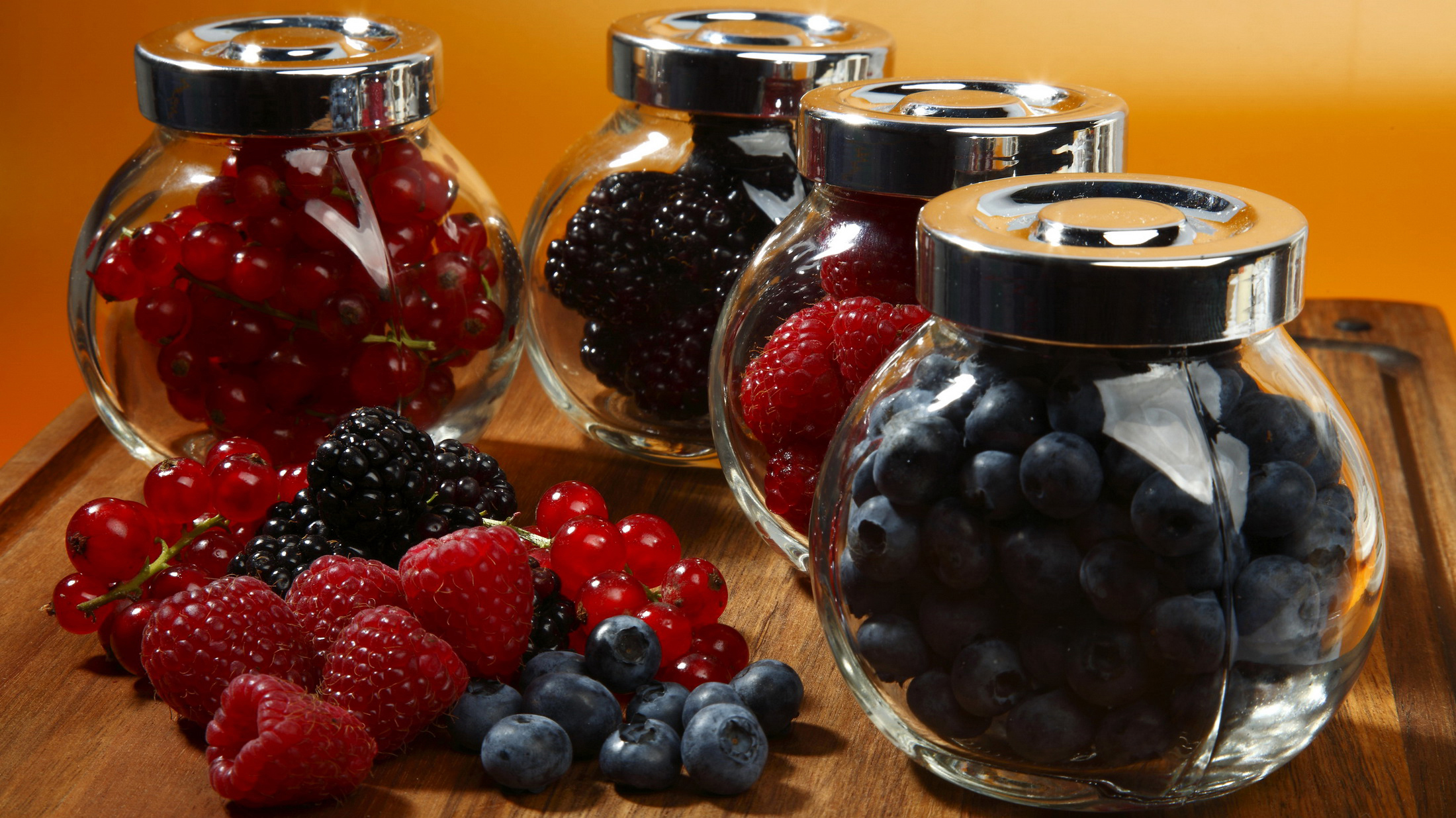 на столе четыре банки ягод и черники