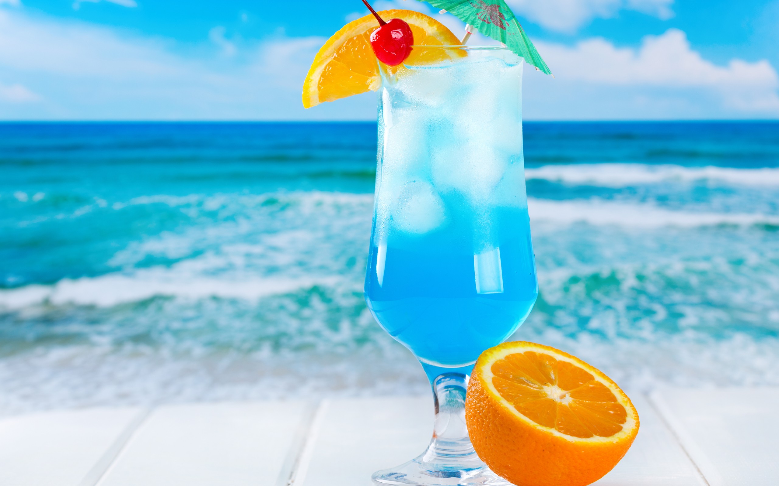Голубой коктейль на берегу с цветками загрузить
