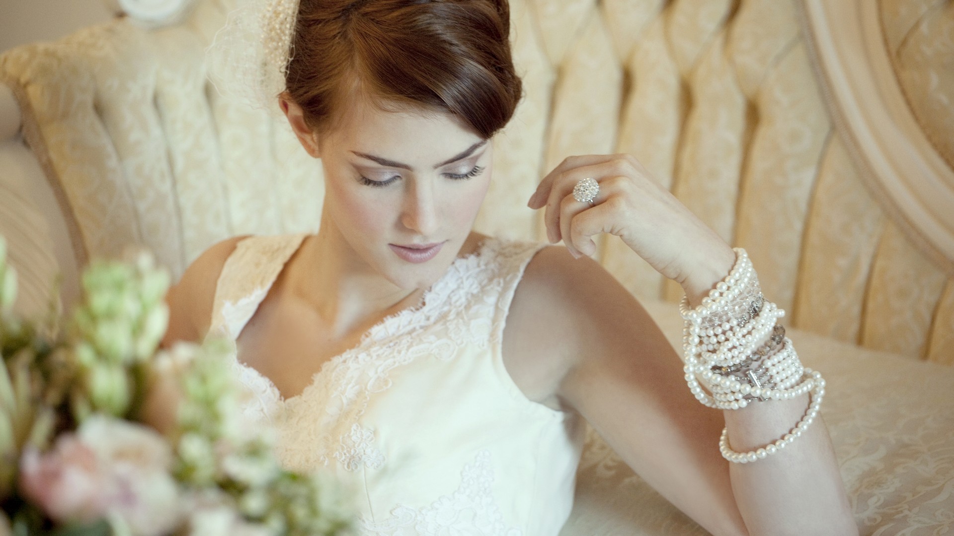 невеста в белом платье сидит на стуле с букетом цветов