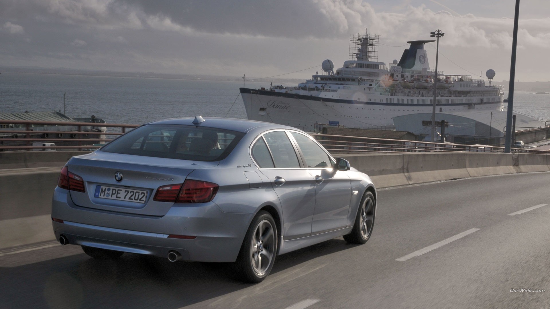 женщина-автомобиль едет по шоссе с круизным судном на заднем плане