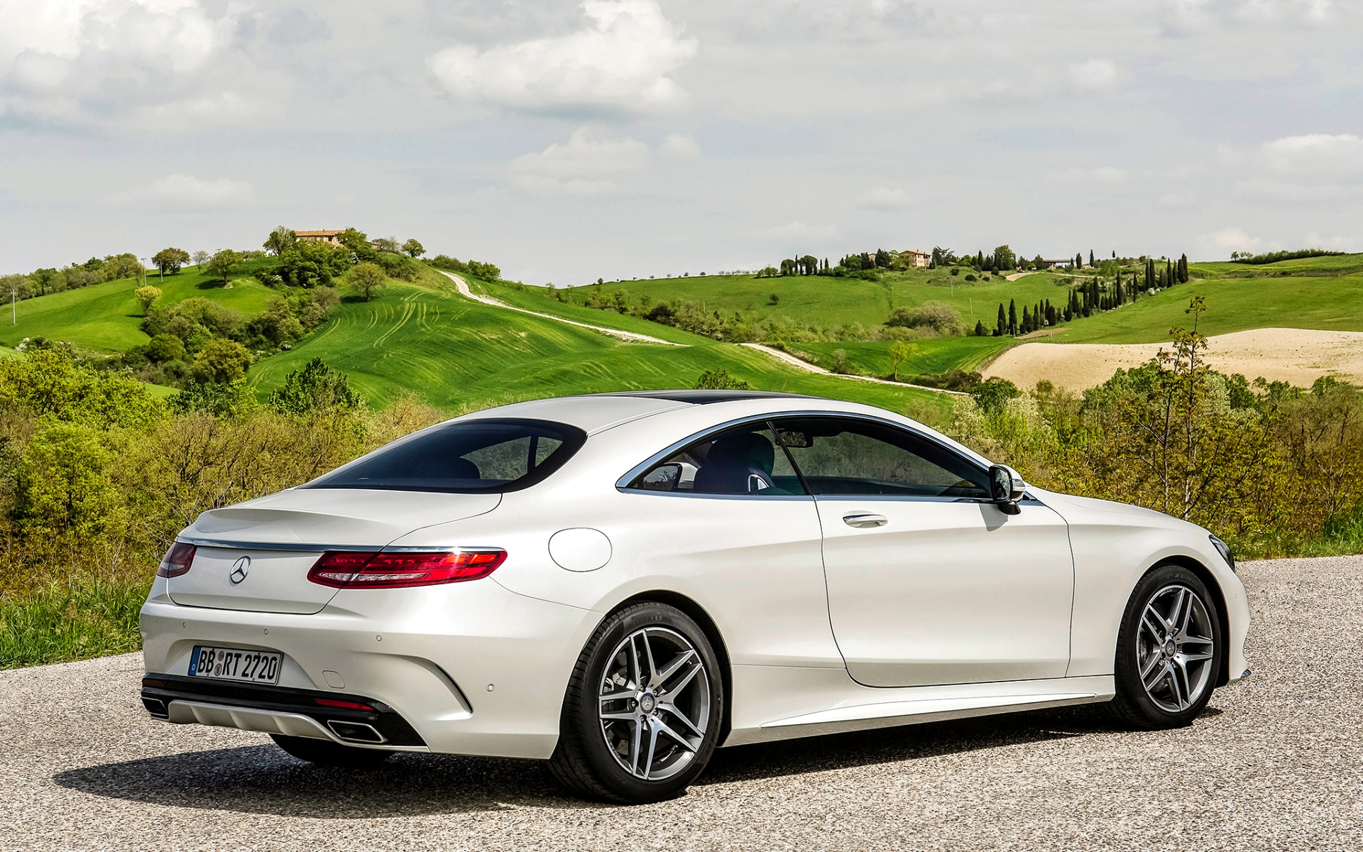 вид белого купе класса mercedes, припаркованного на гравийной дороге