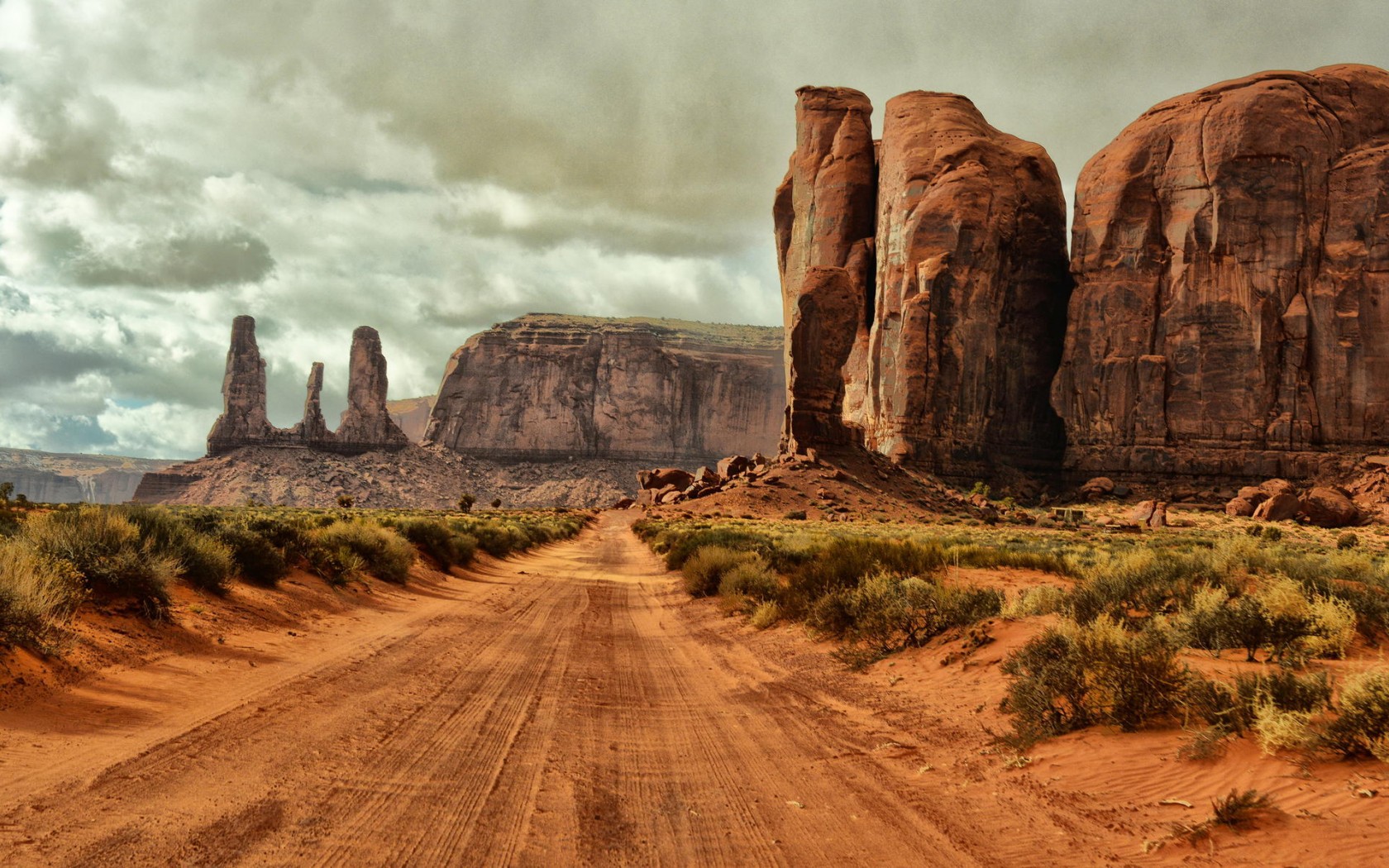 грунтовая дорога в пустыне с камнями и травой с обеих сторон