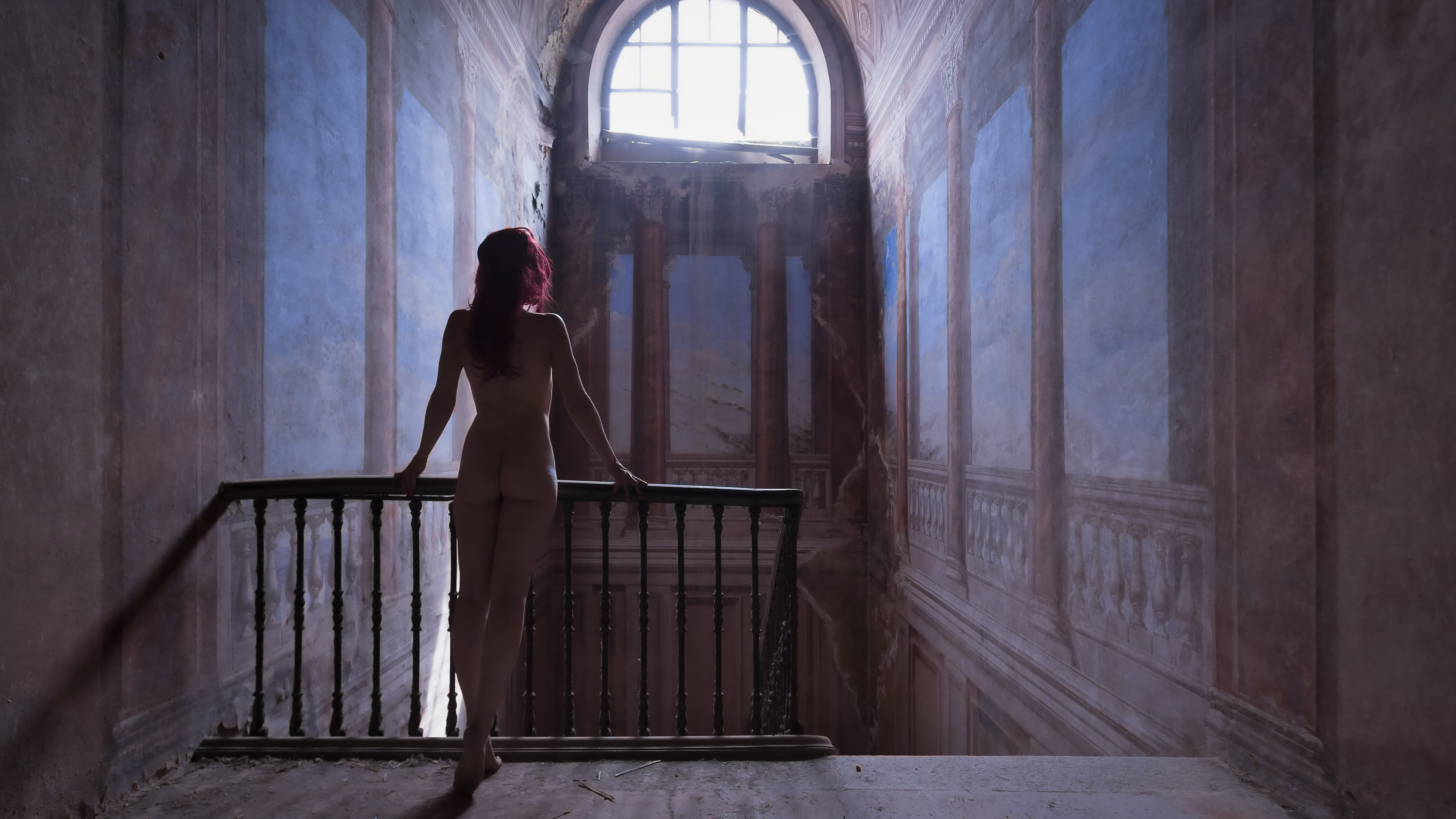 женщина, стоящая на балконе и выглядывающая из окна