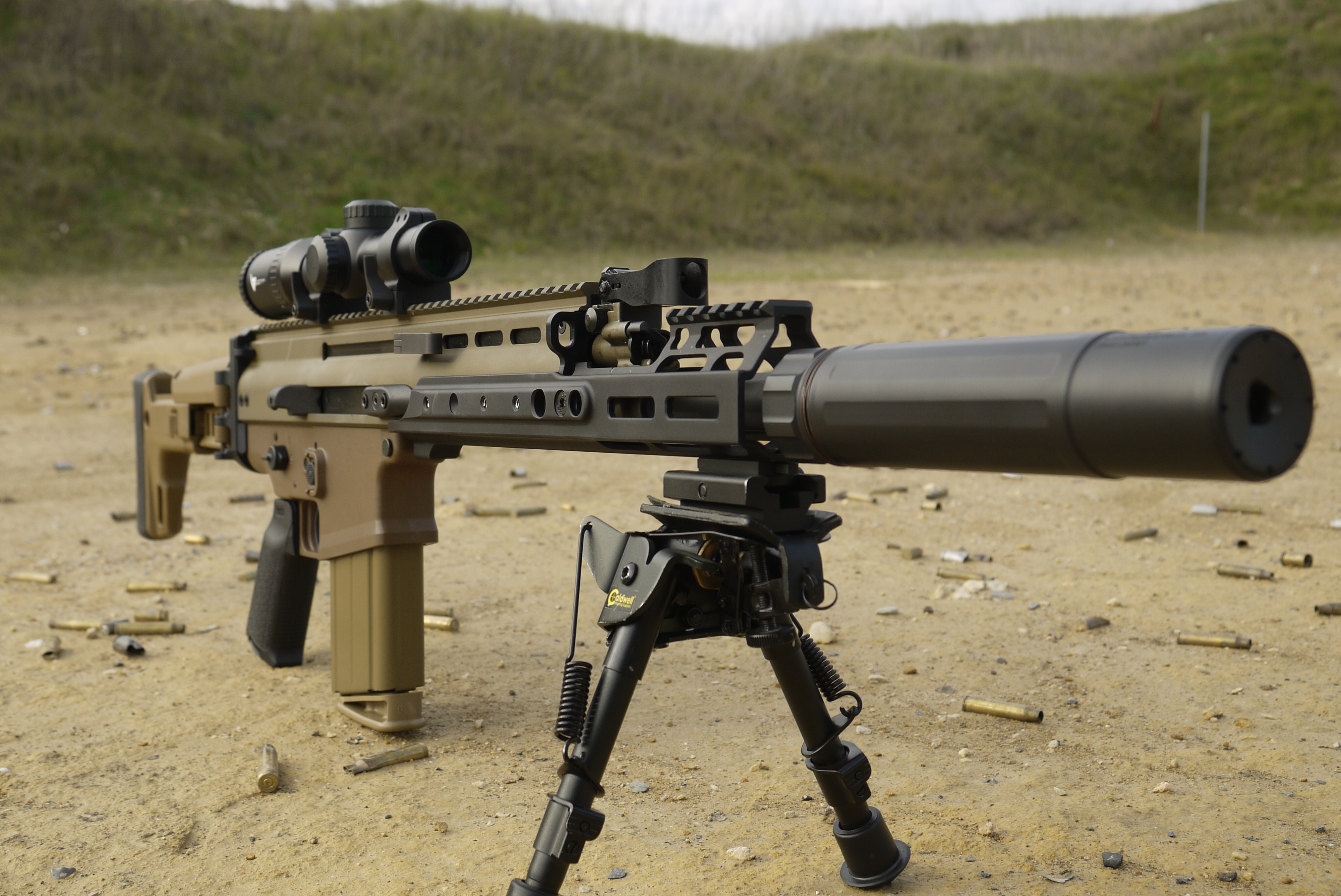 винтовка с прицелом и штативом на пустынной земле