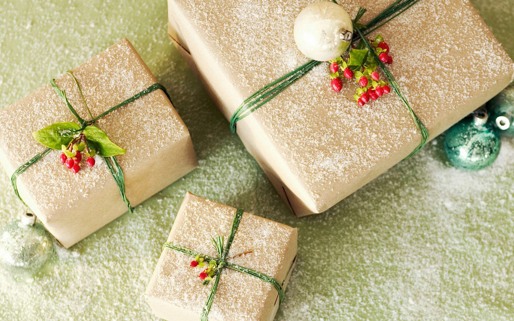 три завернутых подарка с зелеными и красными луками и украшениями